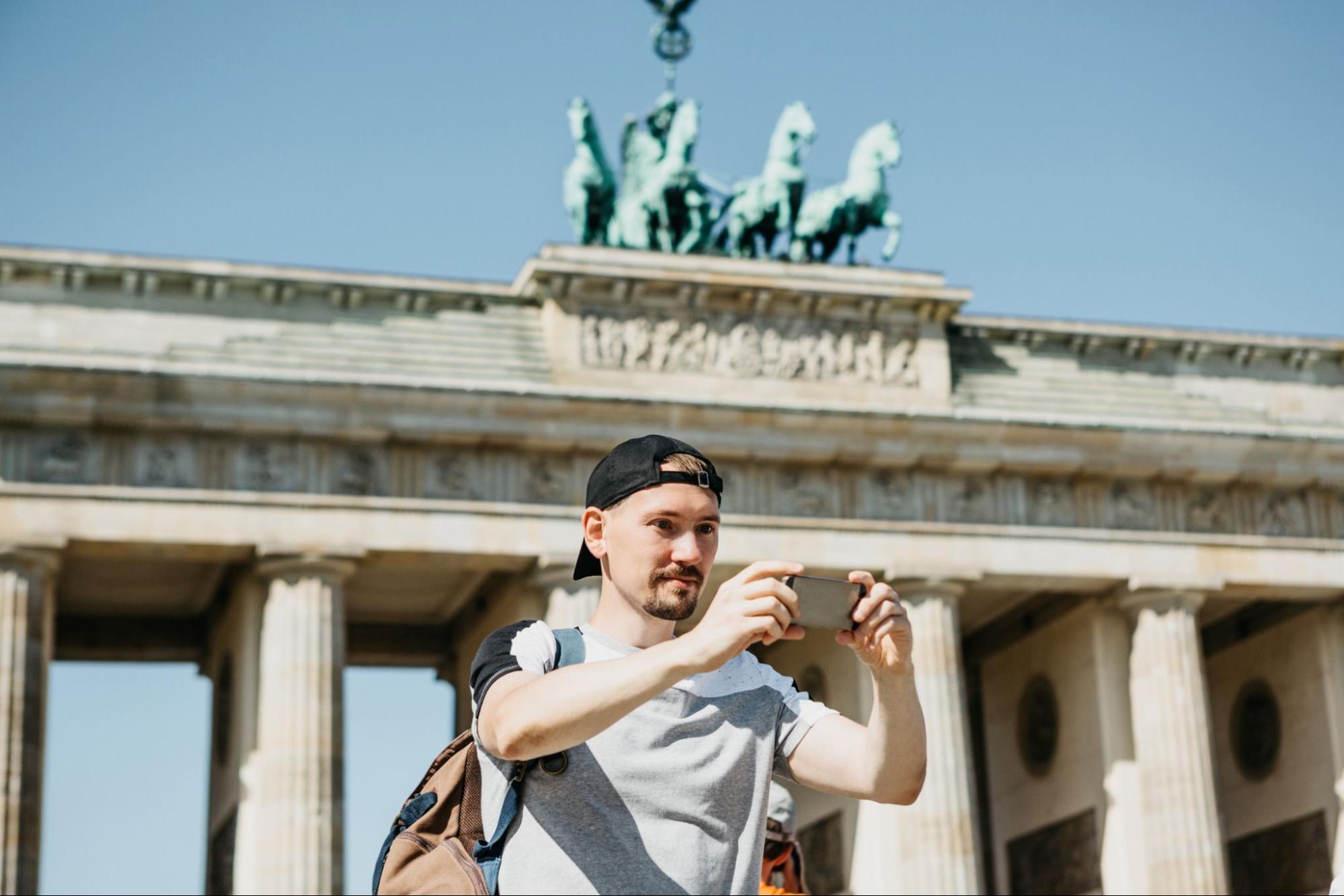 Tourist guy taking a selfie on the background of the Brandenburg Gate in Berlin in Germany or taking pictures of sights